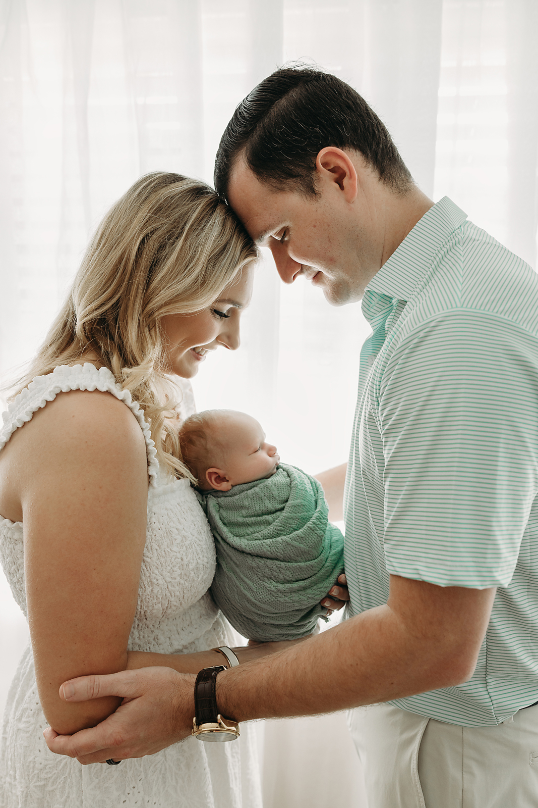 mother and father look down at baby boy 