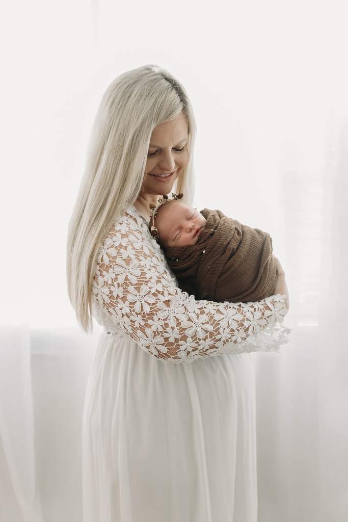 A series of soft, ethereal newborn portraits featuring mom in a white dress