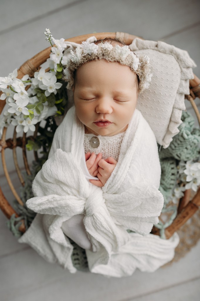 baby girl in white poses naturally with white bow 