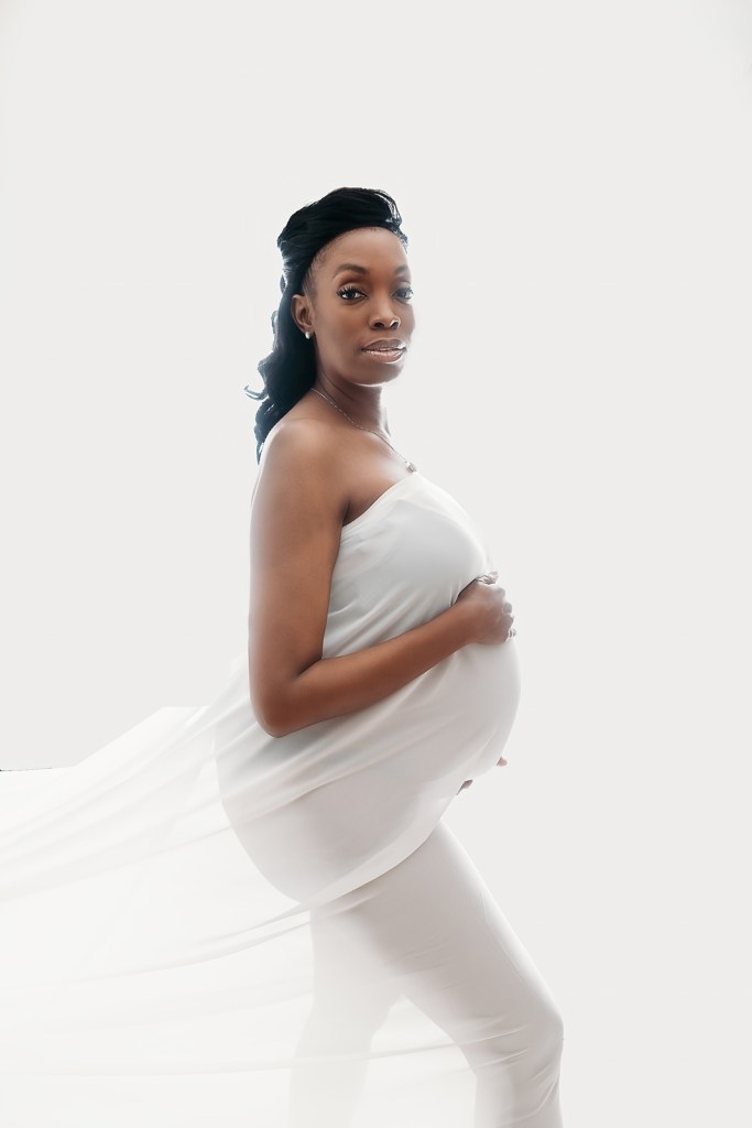 Ethereal maternity portrait of black woman in white sheer silk poses for Tampa maternity photography session