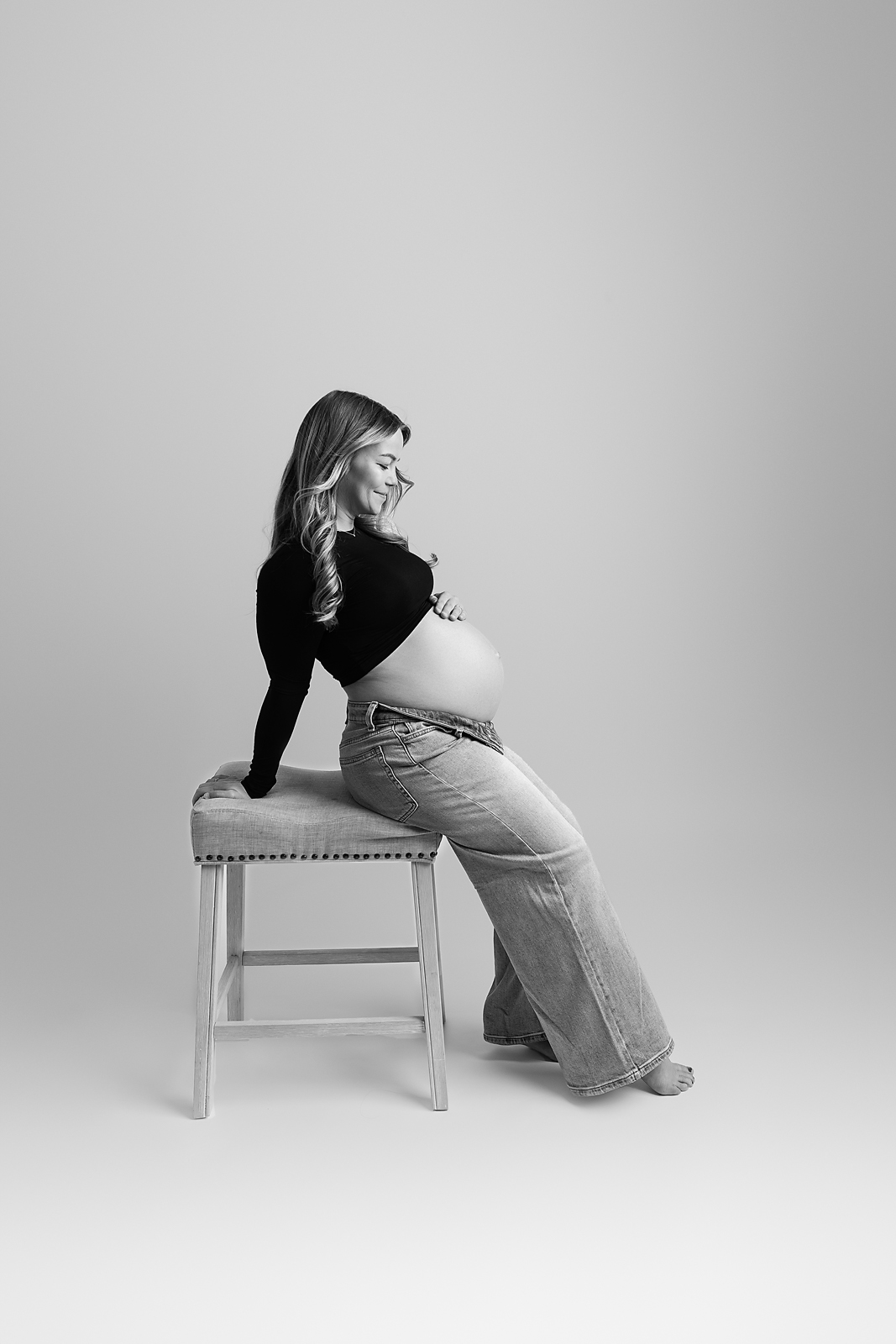 Black and white maternity portrait of mother sitting on a stool taken by Tampa maternity photographer LB Photography, LLC