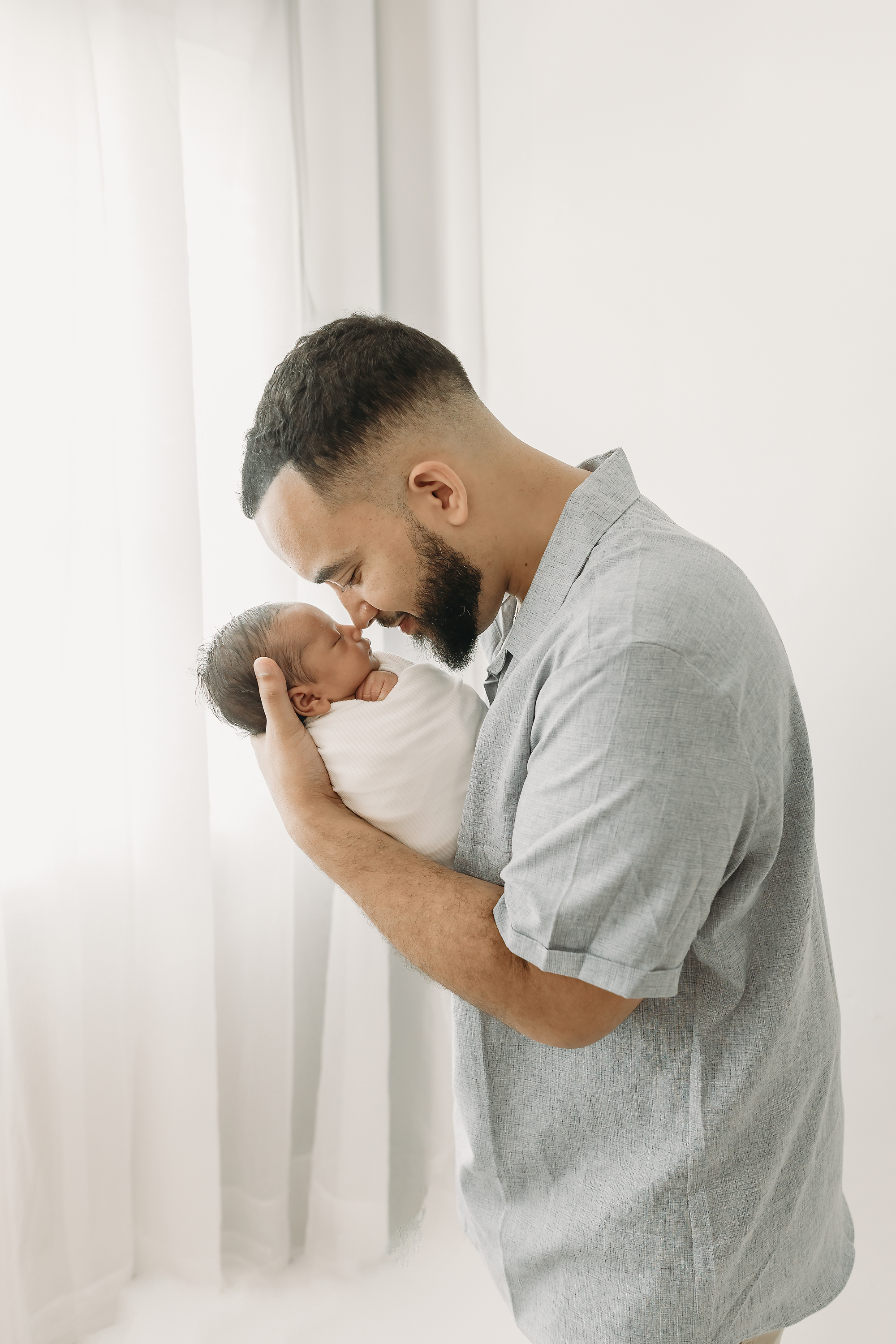 Father holds newborn baby girl up to his nose for eskimo kisses for Tampa newborn photography session