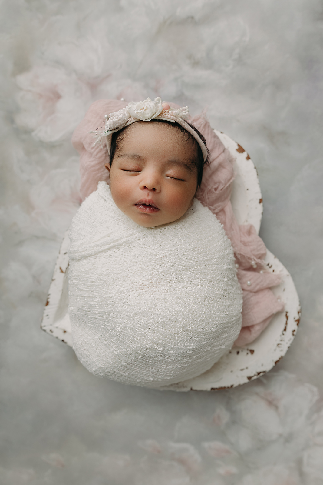 Newborn baby girl peacefully sleeping wrapped in soft white swaddle blanket during Tampa newborn photography session