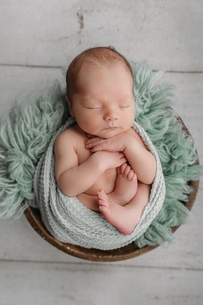 baby boy wrapped in sage green