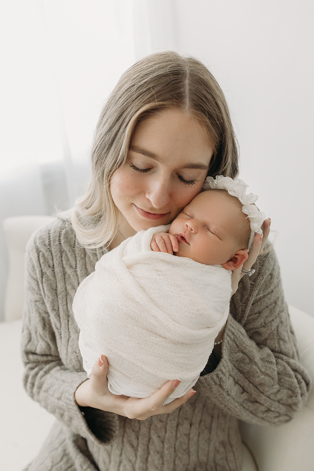 Mother holds newborn baby girl with gentle affection during newborn photos in Tampa
