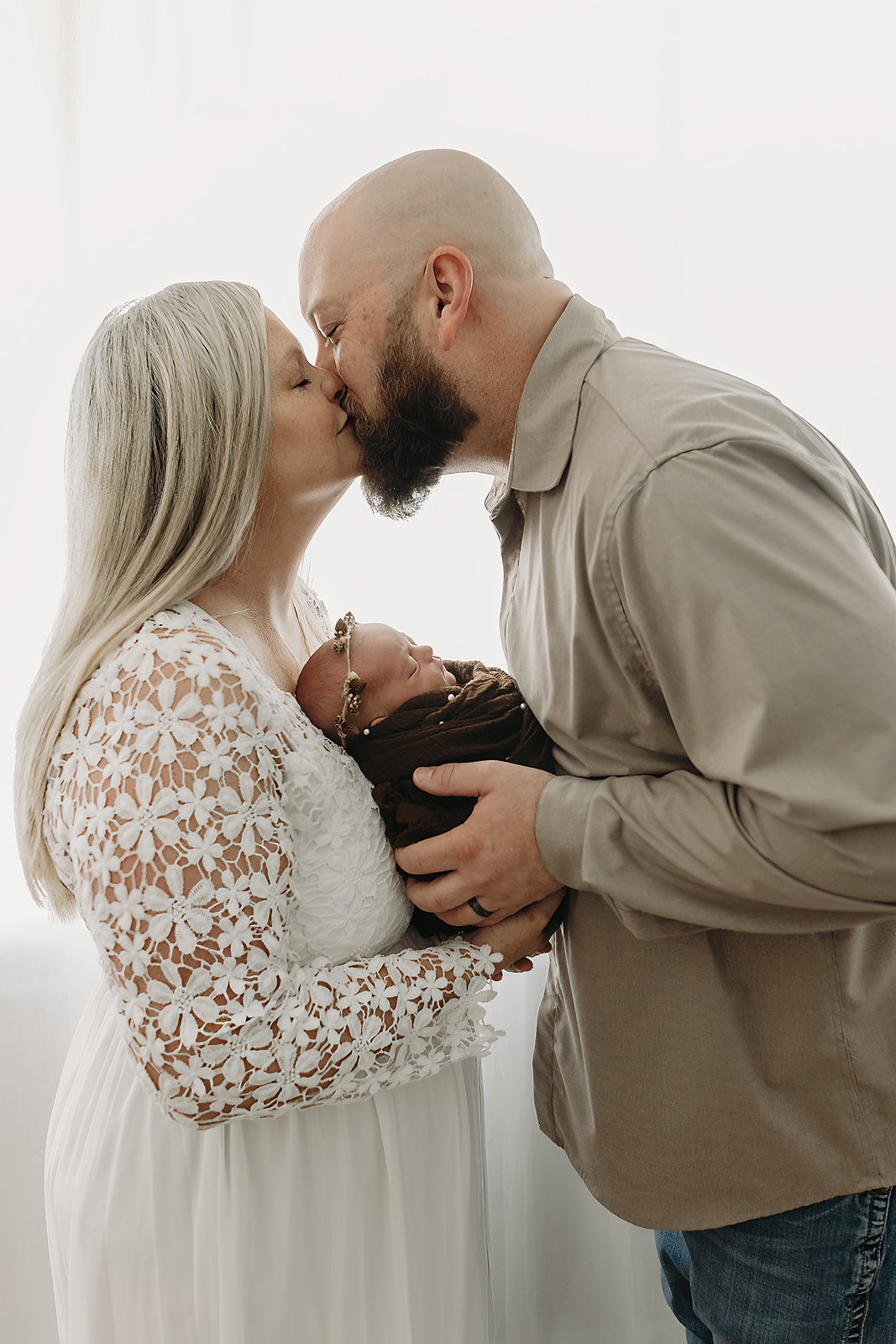 A family portrait in soft white tones featuring a newborn baby wrapped during Tampa newborn photography session