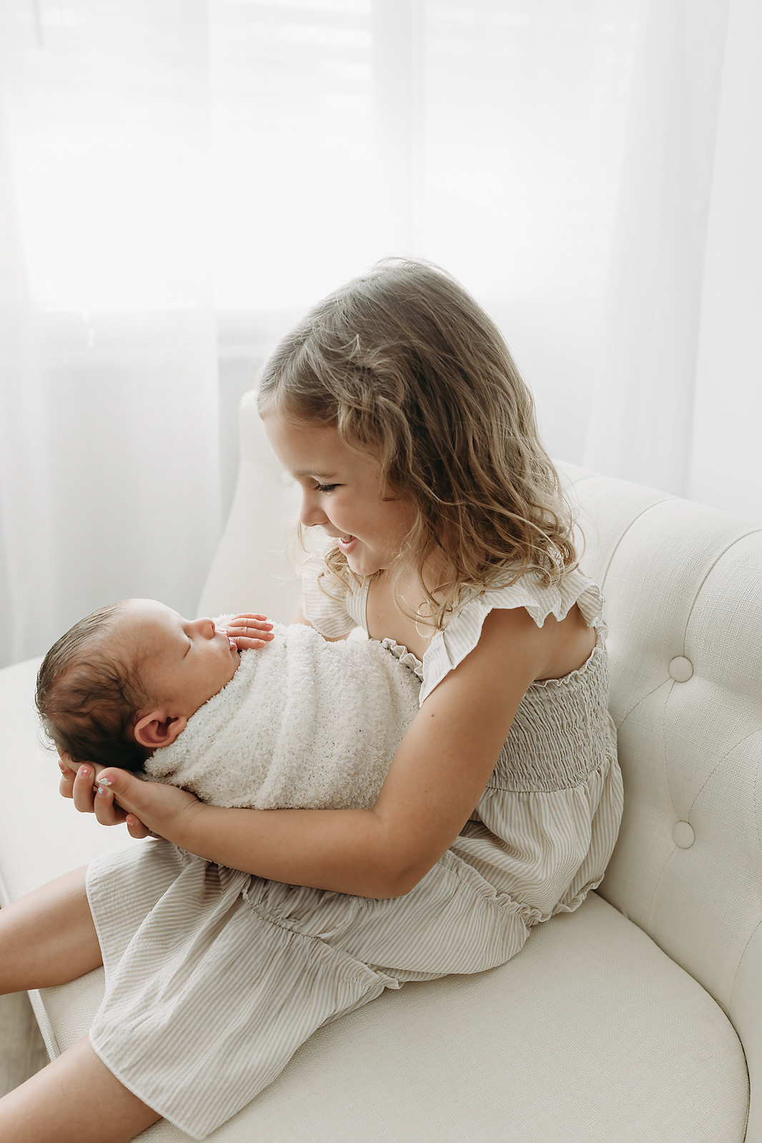 sibling smiles down at her baby brother 