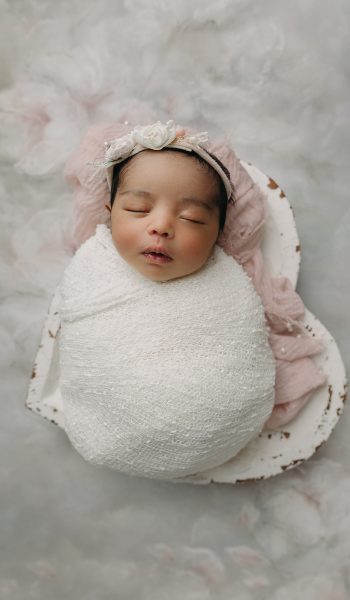 Newborn baby girl peacefully sleeping wrapped in soft white swaddle blanket during Tampa newborn photography session