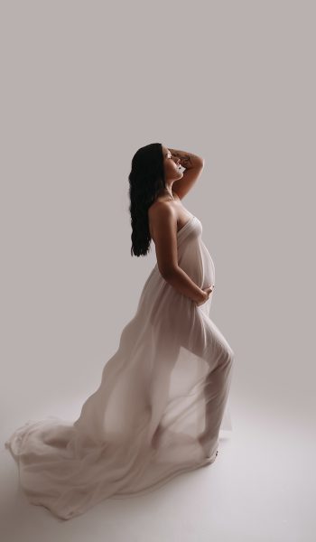 pregnant woman with grey silky fabric poses for her tampa maternity photography session