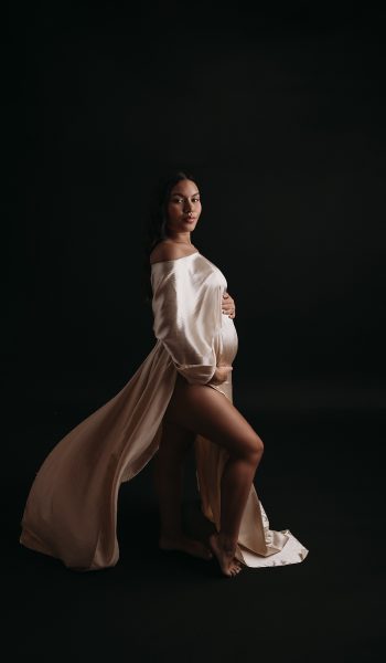 Pregnant woman in gold sheath dress poses for maternity photos in Tampa