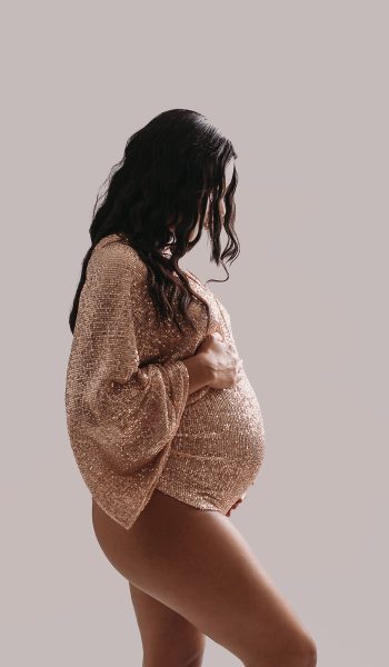 Pregnant woman poses in sparkly gold bodysuit for Tampa maternity photographer