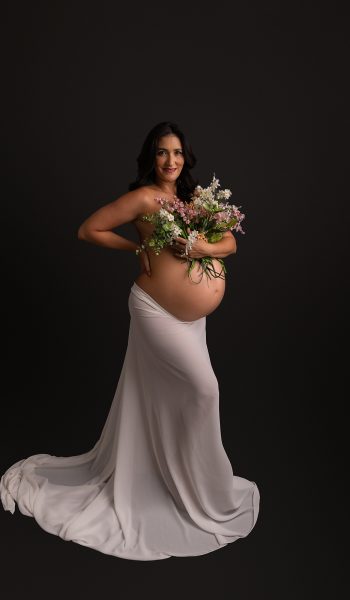 pregnant mother poses in white silk with flowers for tampa maternity photographer