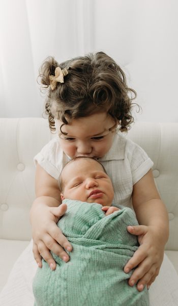 Sister kissing newborn