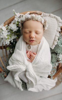 newborn baby girl swaddled in white bow and flowers