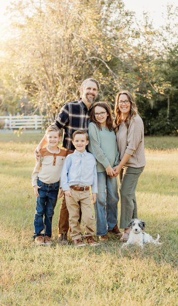 family of five poses outdoors on their family property for tampa family photographer