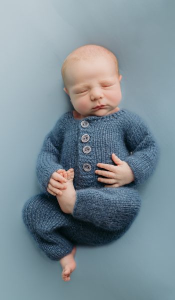 newborn baby boy in blue outfit on blue background
